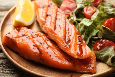 Photo of Seafood. Tasty grilled salmon served with salad and lemon on wooden table, closeup