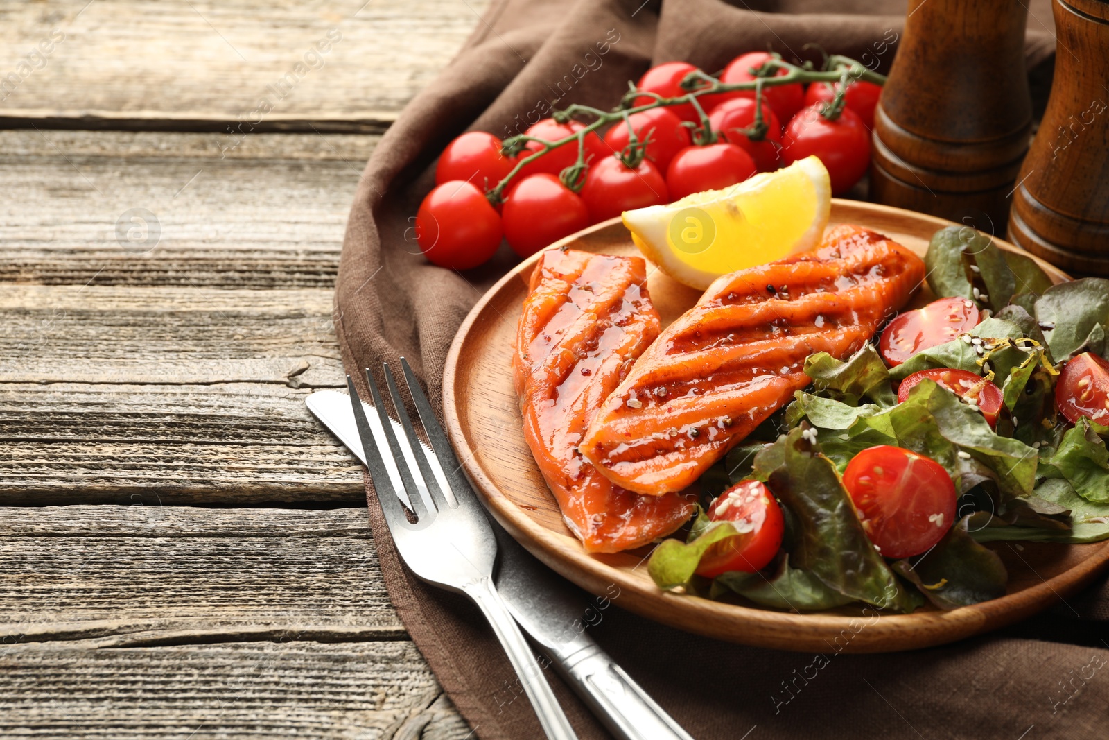 Seafood. Tasty grilled salmon served with cutlery, salad and lemon on wooden table, closeup. Space for text Photo of Seafood. Tasty grilled salmon served with cutlery, salad and lemon on wooden table, closeup. Space for text