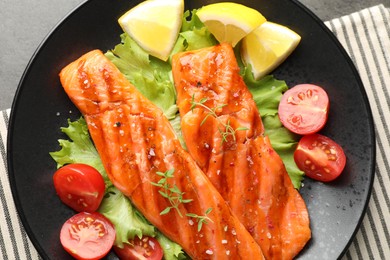 Photo of Tasty grilled salmon served with lettuce, tomatoes and lemon on grey table, top view