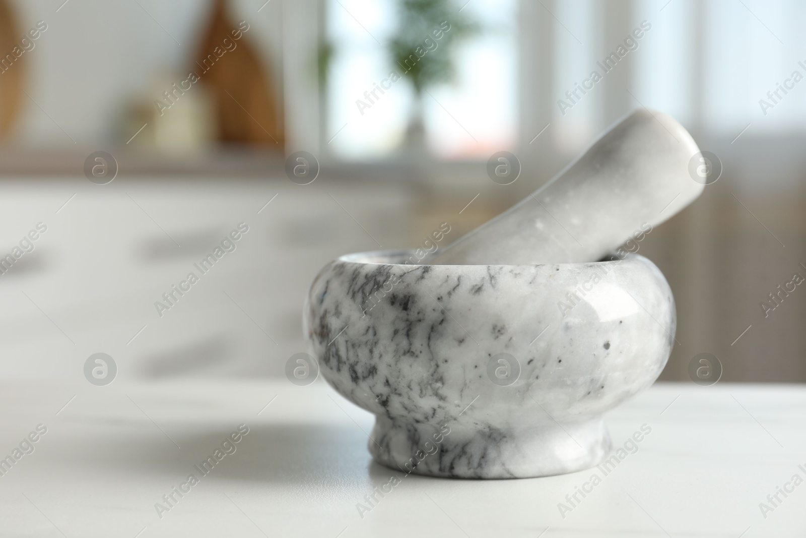 Mortar and pestle on white marble table in kitchen, closeup Photo of Mortar and pestle on white marble table in kitchen, closeup
