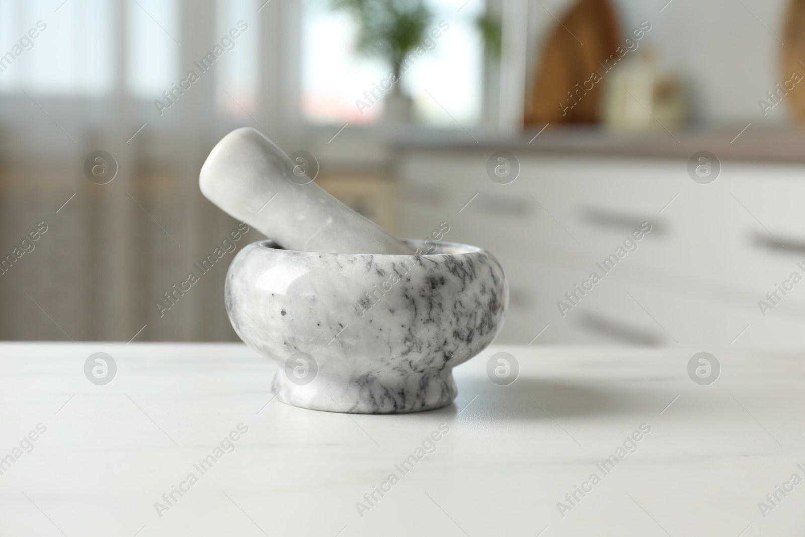 Mortar and pestle on white marble table in kitchen, closeup Photo of Mortar and pestle on white marble table in kitchen, closeup