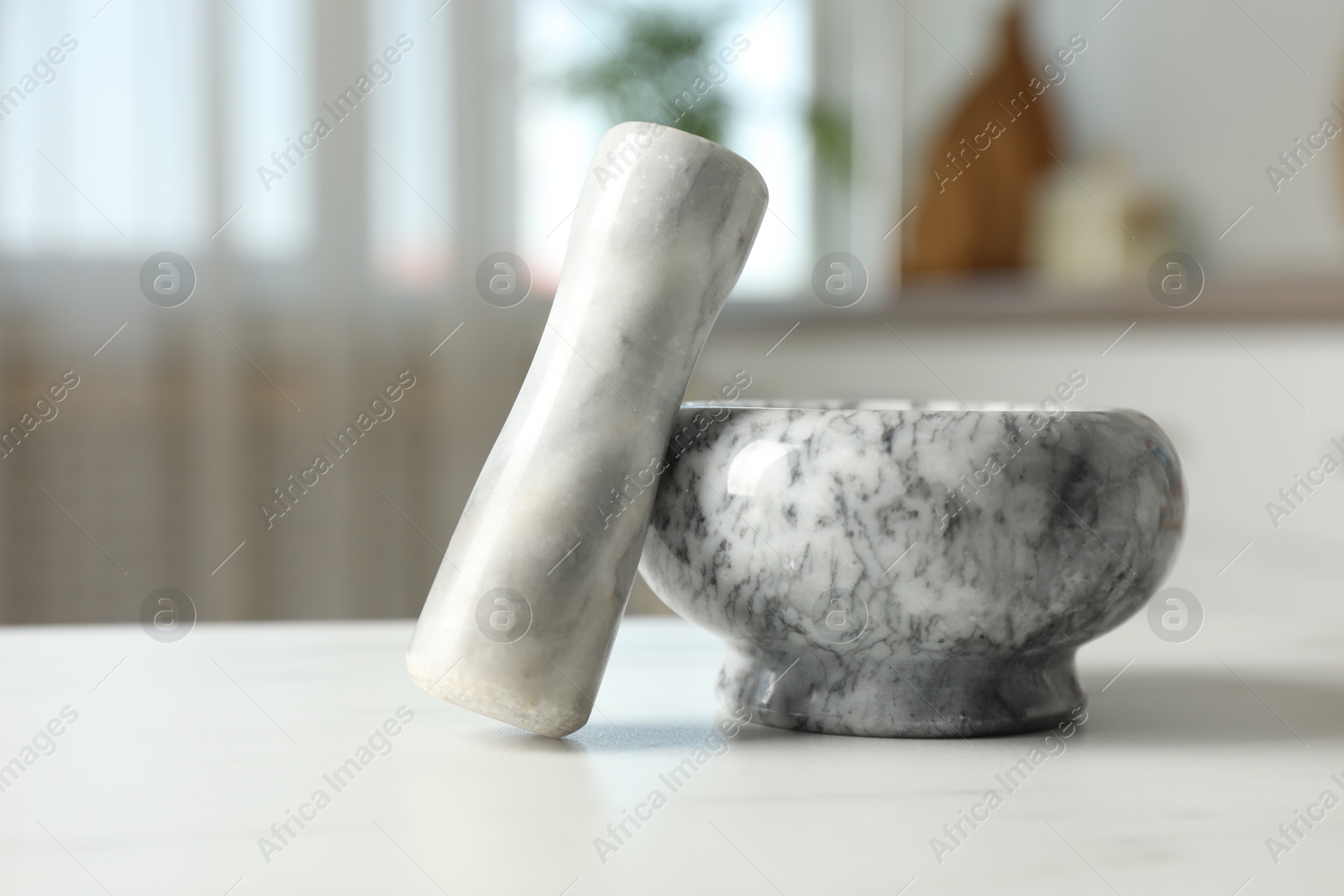 Mortar and pestle on white marble table in kitchen, closeup Photo of Mortar and pestle on white marble table in kitchen, closeup
