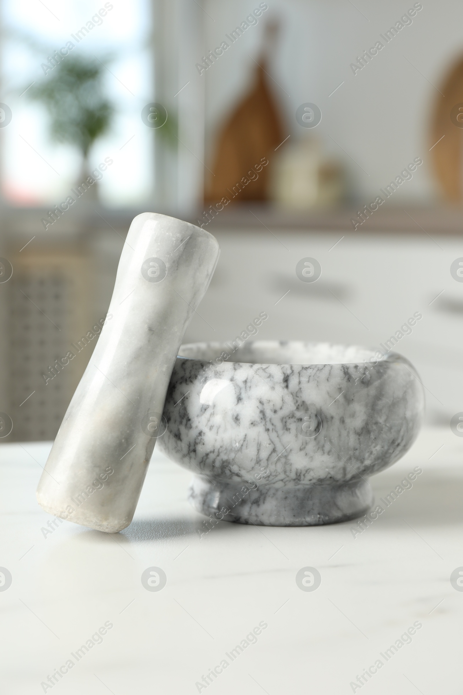 Mortar and pestle on white marble table in kitchen Photo of Mortar and pestle on white marble table in kitchen