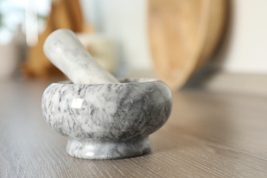 Photo of Marble mortar and pestle on wooden table in kitchen, closeup. Space for text