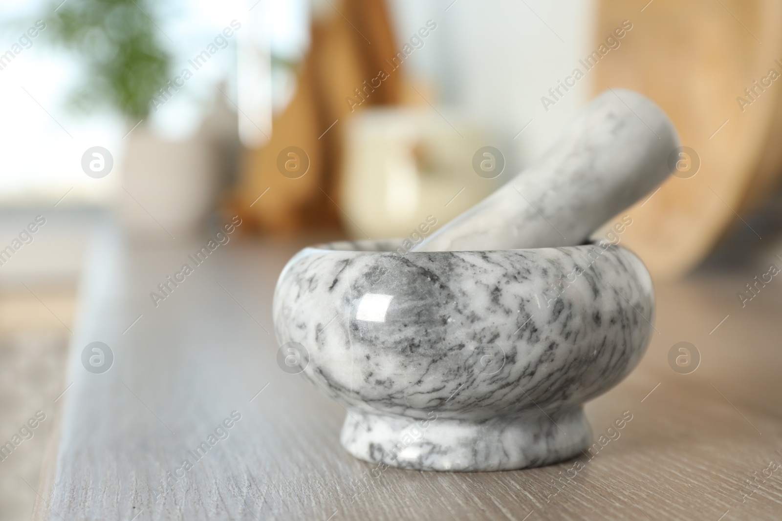 Marble mortar and pestle on wooden table in kitchen, closeup. Space for text Photo of Marble mortar and pestle on wooden table in kitchen, closeup. Space for text