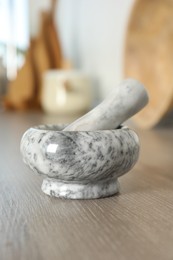 Photo of Marble mortar and pestle on wooden table in kitchen, closeup
