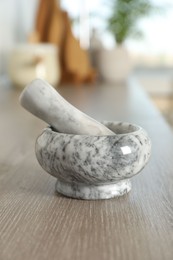 Photo of Marble mortar and pestle on wooden table in kitchen, closeup