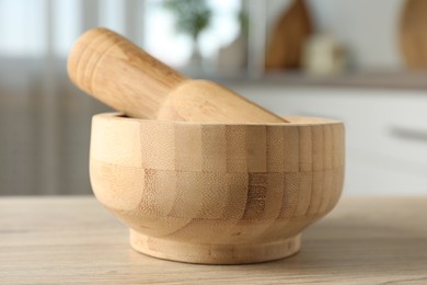 Photo of Mortar and pestle on wooden table in kitchen, closeup