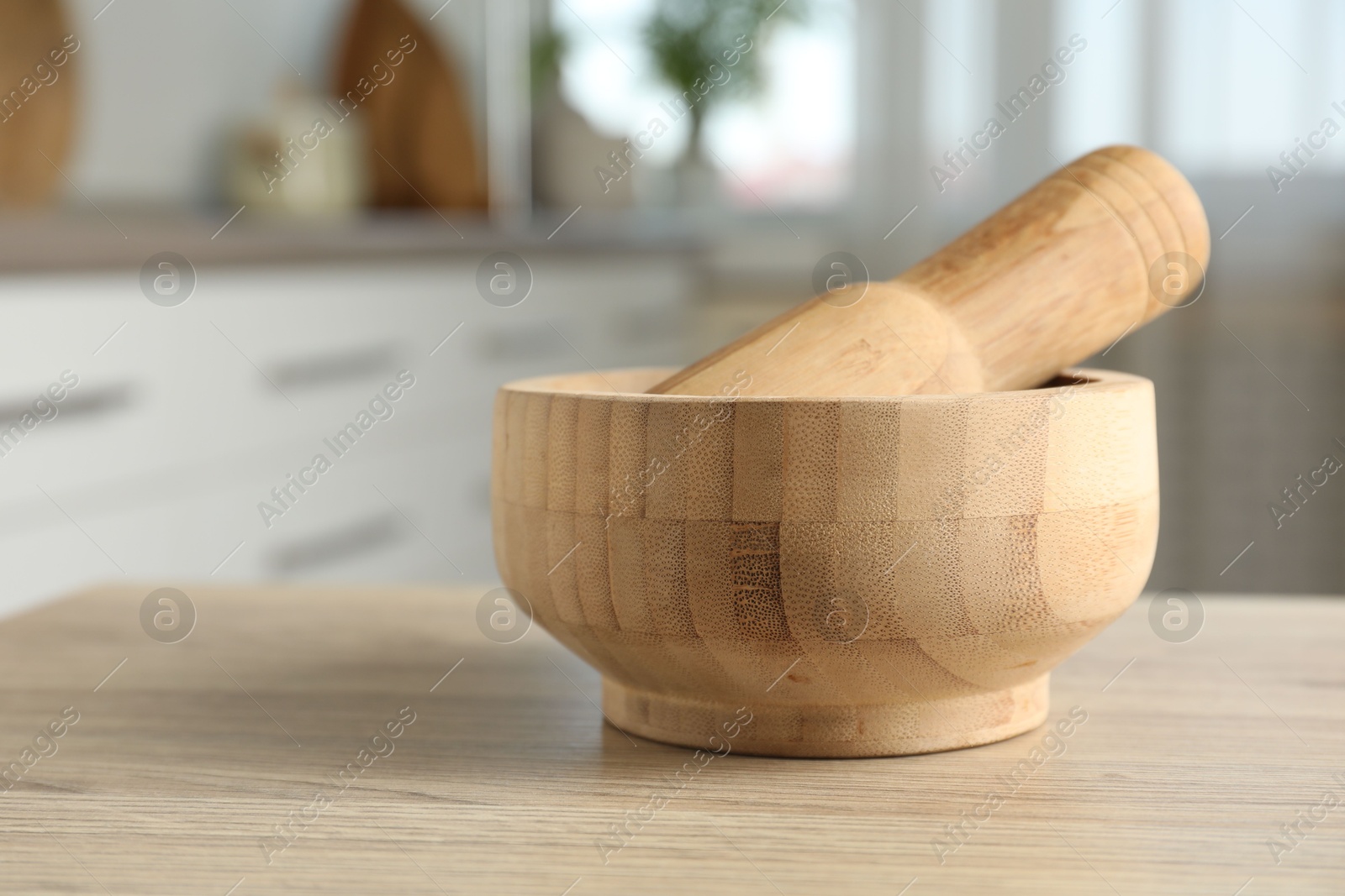 Mortar and pestle on wooden table in kitchen, closeup Photo of Mortar and pestle on wooden table in kitchen, closeup