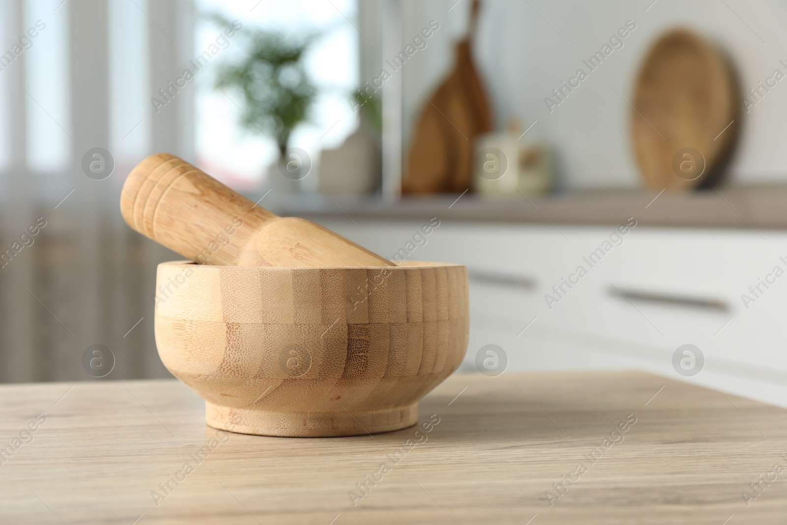 Mortar and pestle on wooden table in kitchen, closeup. Space for text Photo of Mortar and pestle on wooden table in kitchen, closeup. Space for text
