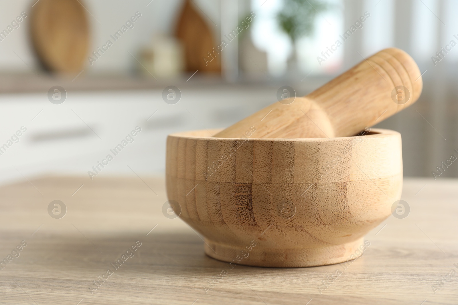 Mortar and pestle on wooden table in kitchen, closeup Photo of Mortar and pestle on wooden table in kitchen, closeup