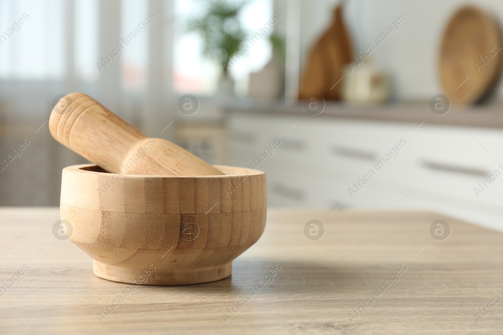 Mortar and pestle on wooden table in kitchen, closeup. Space for text Photo of Mortar and pestle on wooden table in kitchen, closeup. Space for text