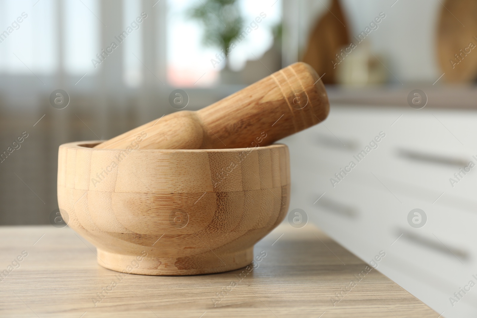 Mortar and pestle on wooden table in kitchen, closeup Photo of Mortar and pestle on wooden table in kitchen, closeup