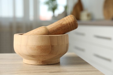 Photo of Mortar and pestle on wooden table in kitchen, closeup