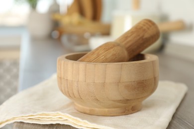 Photo of Mortar and pestle on wooden table in kitchen, closeup