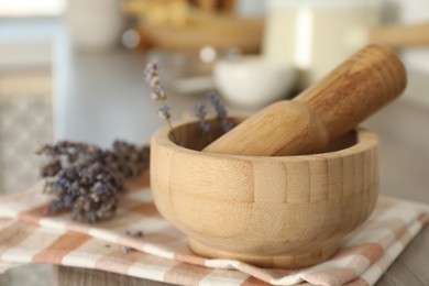 Photo of Mortar with lavender and pestle on wooden table in kitchen, closeup