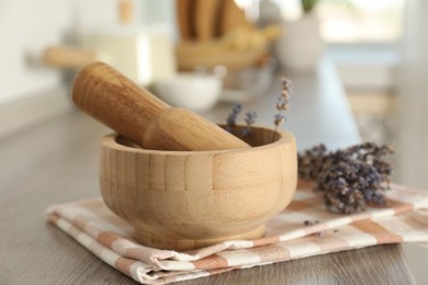 Photo of Mortar with lavender and pestle on wooden table in kitchen, closeup