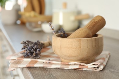 Photo of Mortar with lavender and pestle on wooden table in kitchen