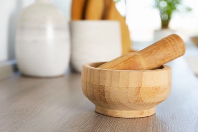 Photo of Mortar and pestle on wooden table in kitchen, closeup. Space for text