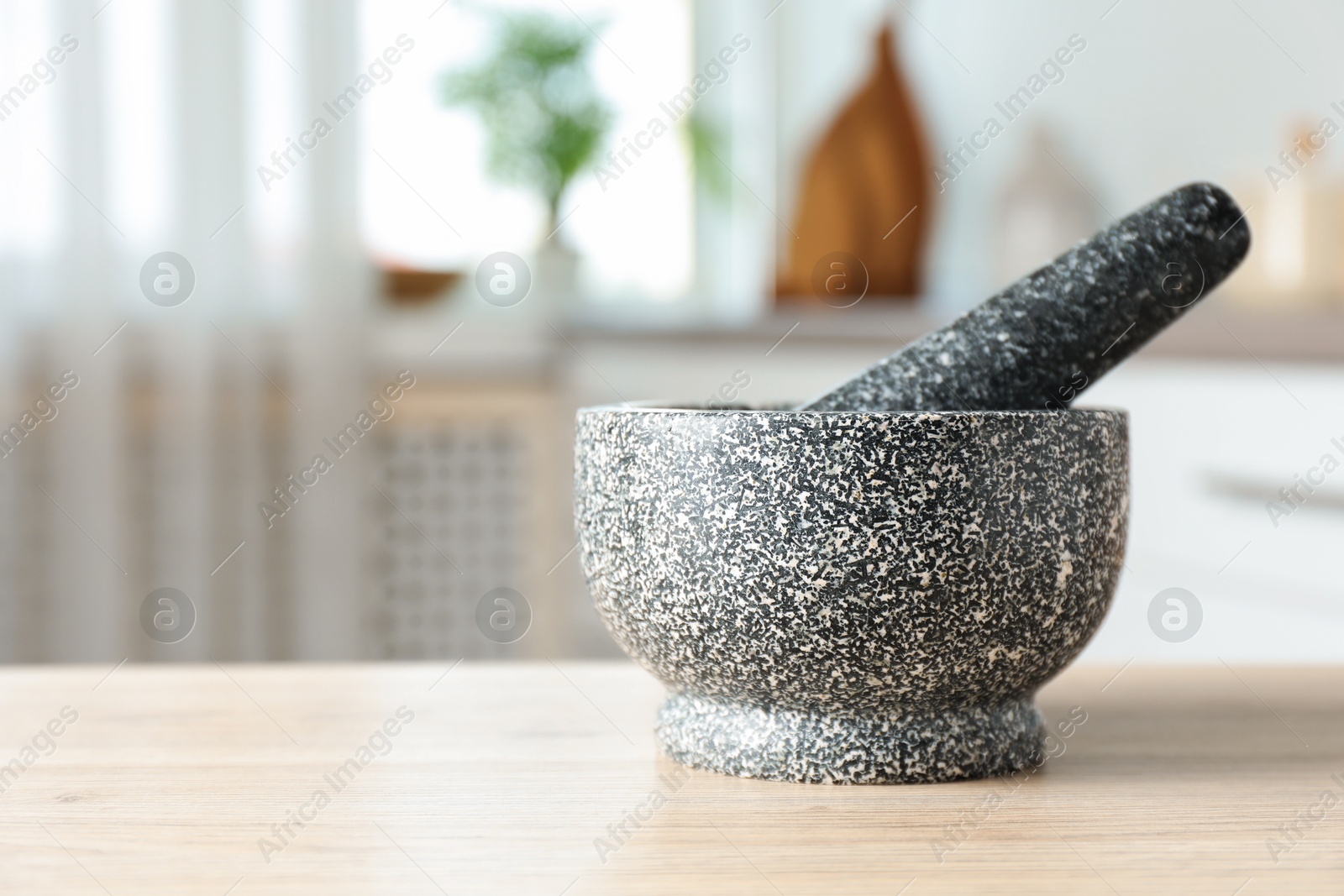 Stone mortar and pestle on wooden table in kitchen, closeup. Space for text Photo of Stone mortar and pestle on wooden table in kitchen, closeup. Space for text