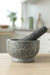 Photo of Stone mortar and pestle on wooden table in kitchen