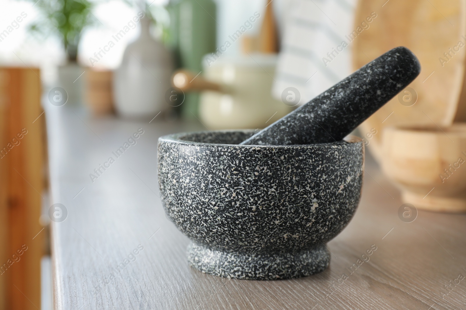 Stone mortar and pestle on wooden table in kitchen Photo of Stone mortar and pestle on wooden table in kitchen