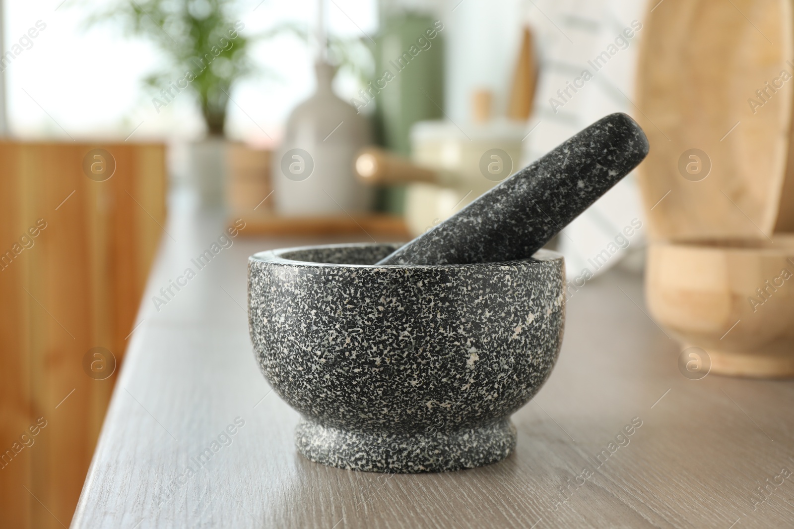 Stone mortar and pestle on wooden table in kitchen Photo of Stone mortar and pestle on wooden table in kitchen
