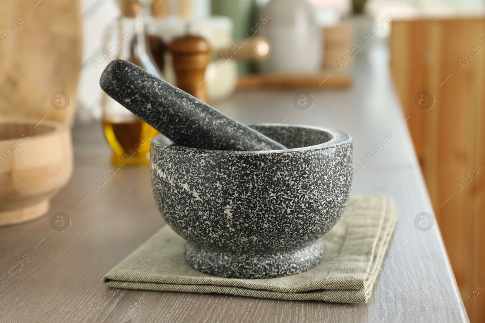 Stone mortar and pestle on wooden table in kitchen Photo of Stone mortar and pestle on wooden table in kitchen