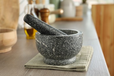 Photo of Stone mortar and pestle on wooden table in kitchen