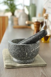 Photo of Stone mortar and pestle on wooden table in kitchen