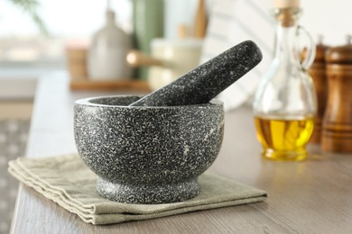 Photo of Stone mortar and pestle on wooden table in kitchen