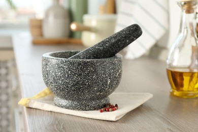 Photo of Stone mortar, pestle and spices on wooden table in kitchen