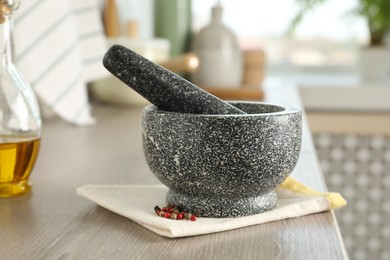Photo of Stone mortar, pestle and spices on wooden table in kitchen