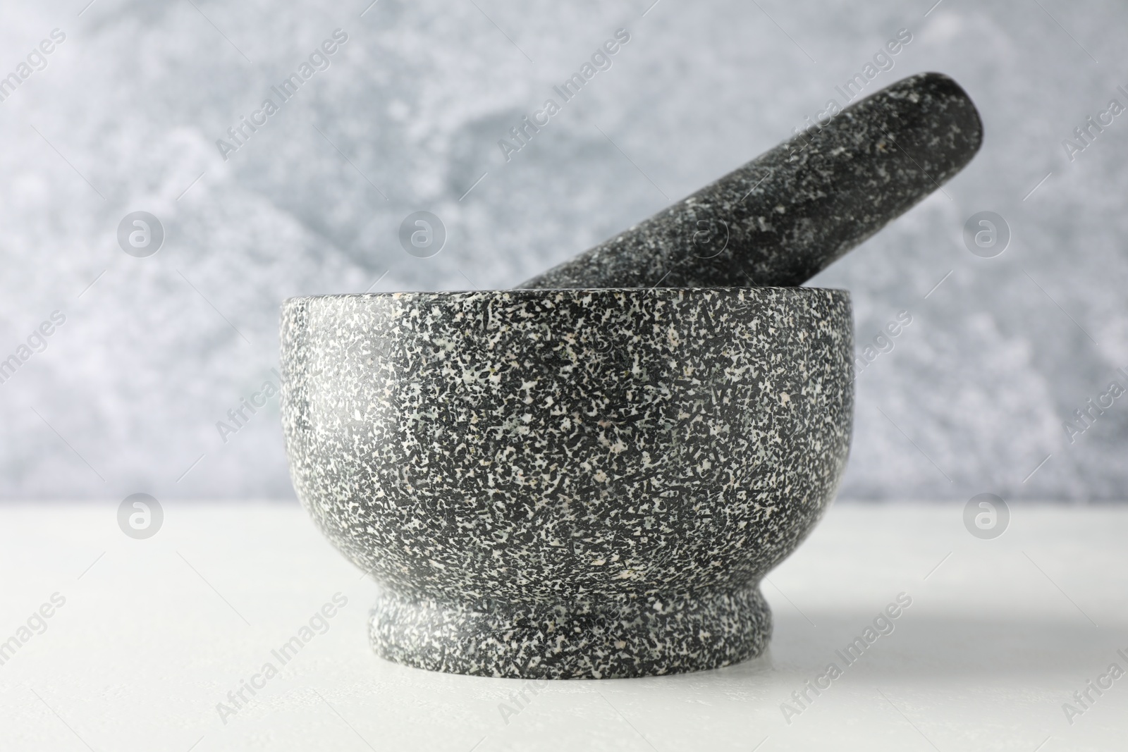 Stone mortar and pestle on white table, closeup Photo of Stone mortar and pestle on white table, closeup