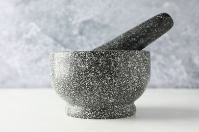 Photo of Stone mortar and pestle on white table, closeup
