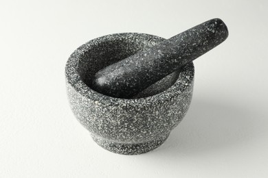 Photo of Stone mortar and pestle on white table, closeup