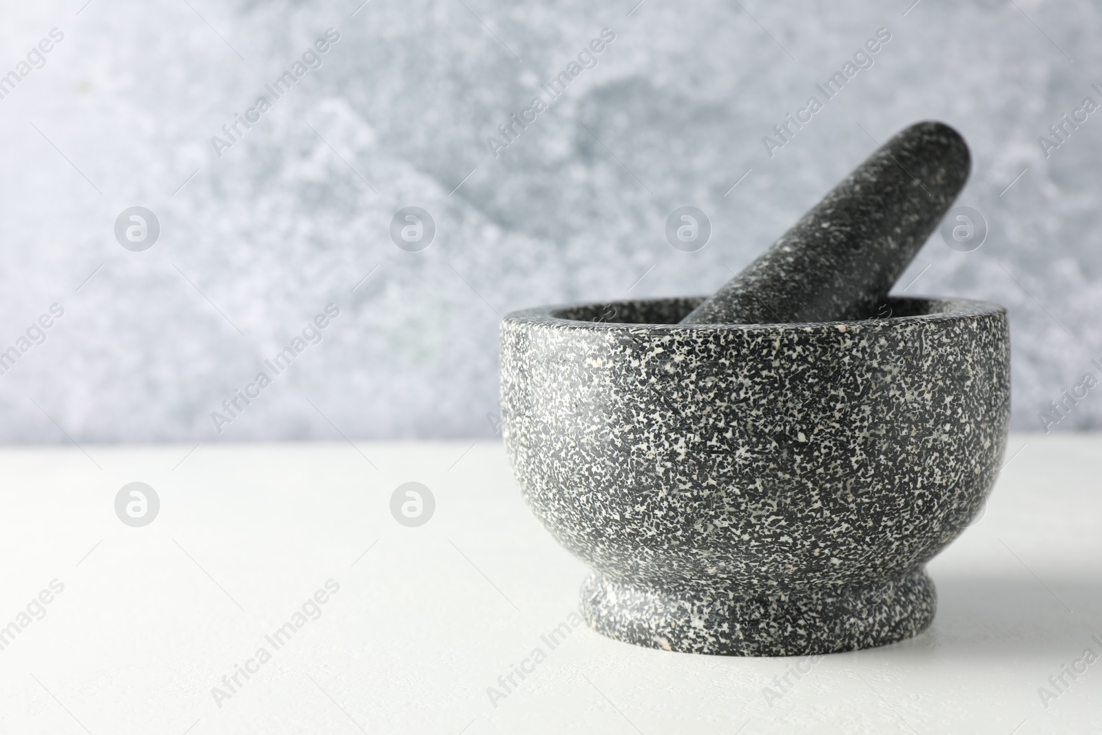 Stone mortar and pestle on white table, closeup. Space for text Photo of Stone mortar and pestle on white table, closeup. Space for text