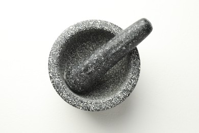 Photo of Stone mortar and pestle on white table, top view