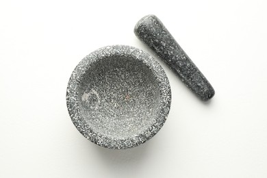 Photo of Stone mortar and pestle on white table, top view