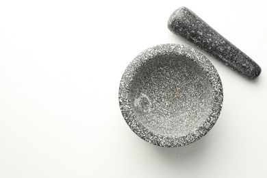 Photo of Stone mortar and pestle on white table, top view. Space for text