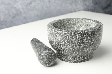 Photo of Stone mortar and pestle on white table, closeup