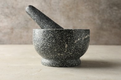 Photo of Stone mortar and pestle on light table, closeup