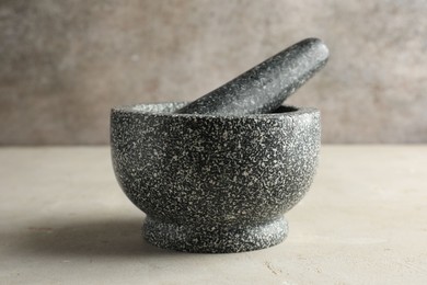 Photo of Stone mortar and pestle on light table, closeup