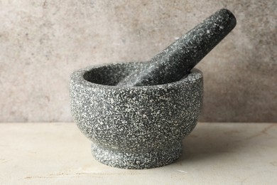 Photo of Stone mortar and pestle on light table, closeup