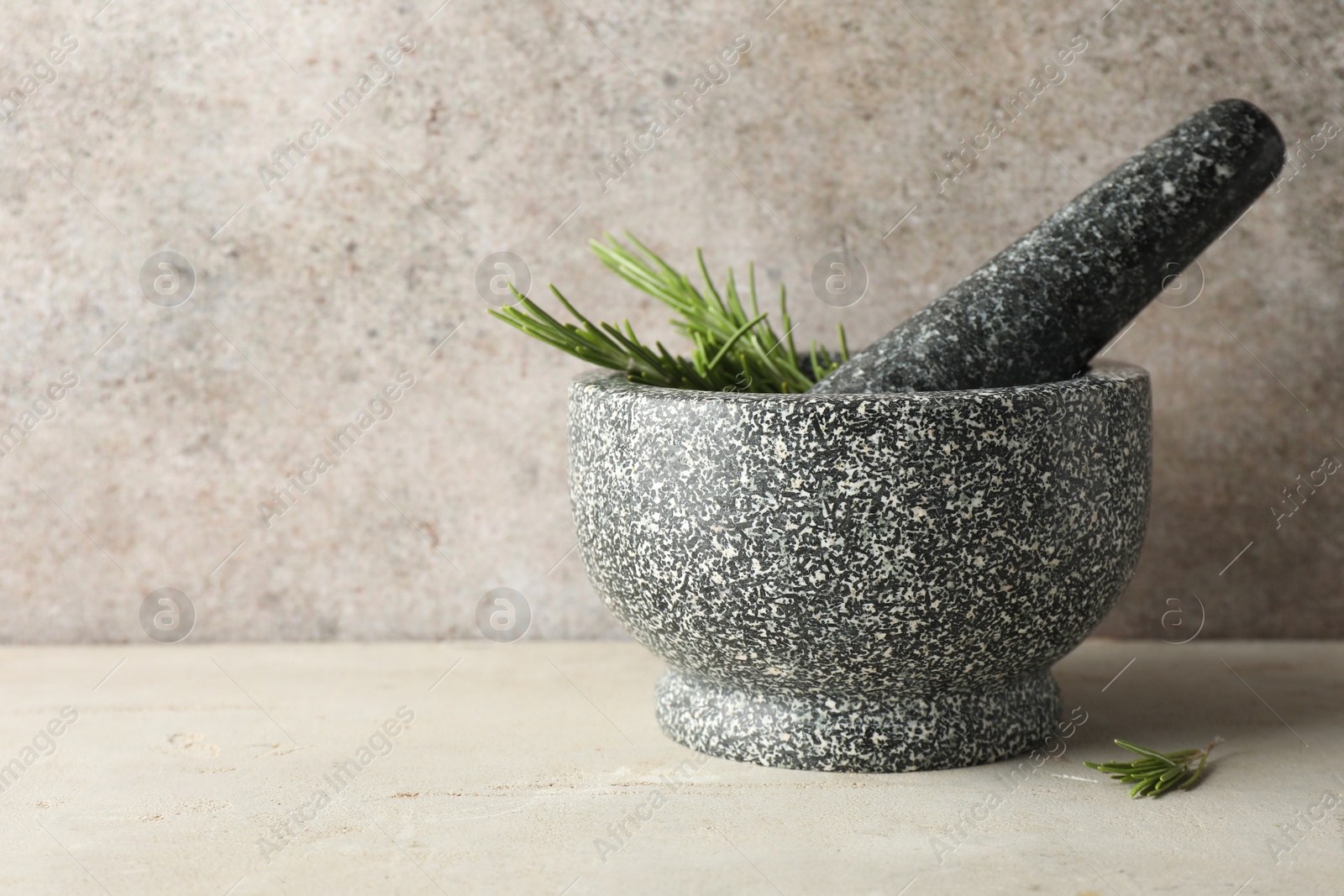 Stone mortar with rosemary and pestle on light table, closeup. Space for text Photo of Stone mortar with rosemary and pestle on light table, closeup. Space for text