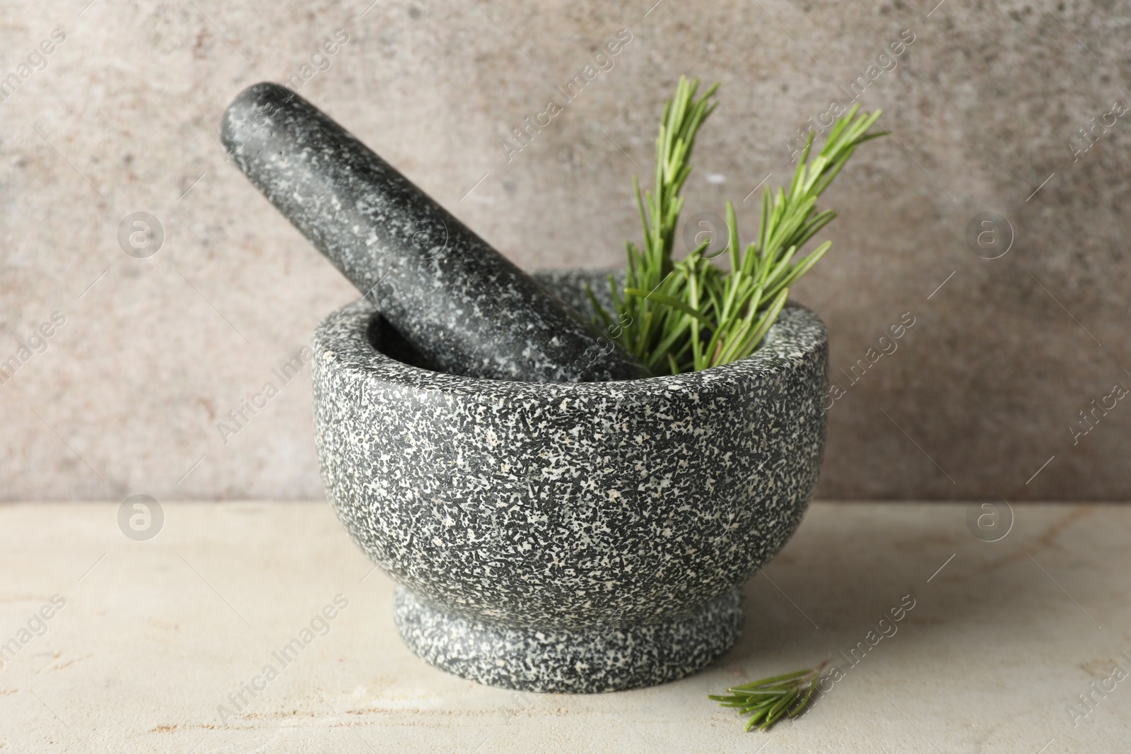 Stone mortar with rosemary and pestle on light table, closeup Photo of Stone mortar with rosemary and pestle on light table, closeup