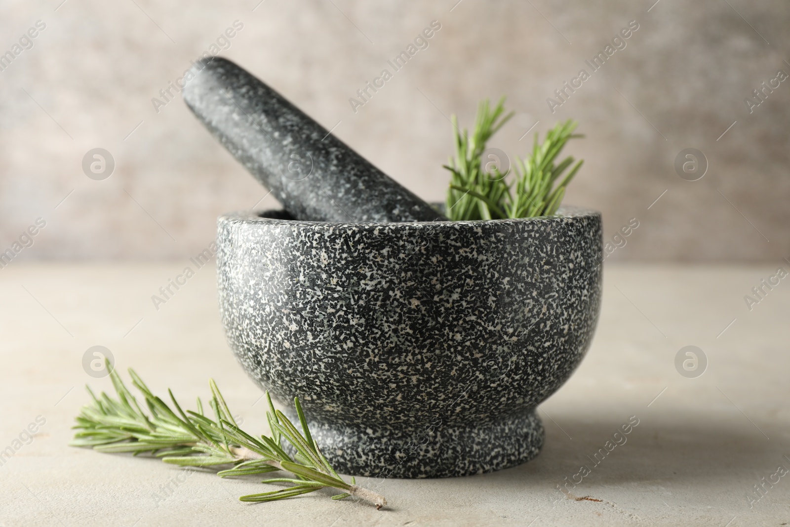 Stone mortar with rosemary and pestle on light table, closeup Photo of Stone mortar with rosemary and pestle on light table, closeup