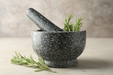 Photo of Stone mortar with rosemary and pestle on light table, closeup