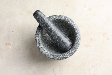 Photo of Stone mortar and pestle on light table, top view
