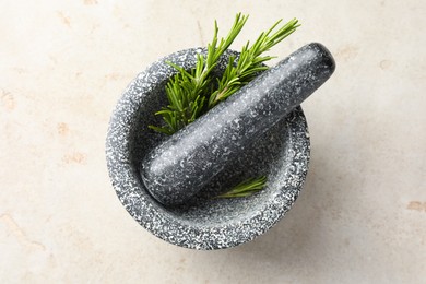 Photo of Stone mortar with rosemary and pestle on light table, top view